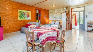 A cozy room with a wooden wall, a dining table with chairs, a sofa, and a stone wall. - Holiday Home 'Gîte - Le Samiege' with Private Terrace, Shared Garden and Wi-Fi (Goudargues)