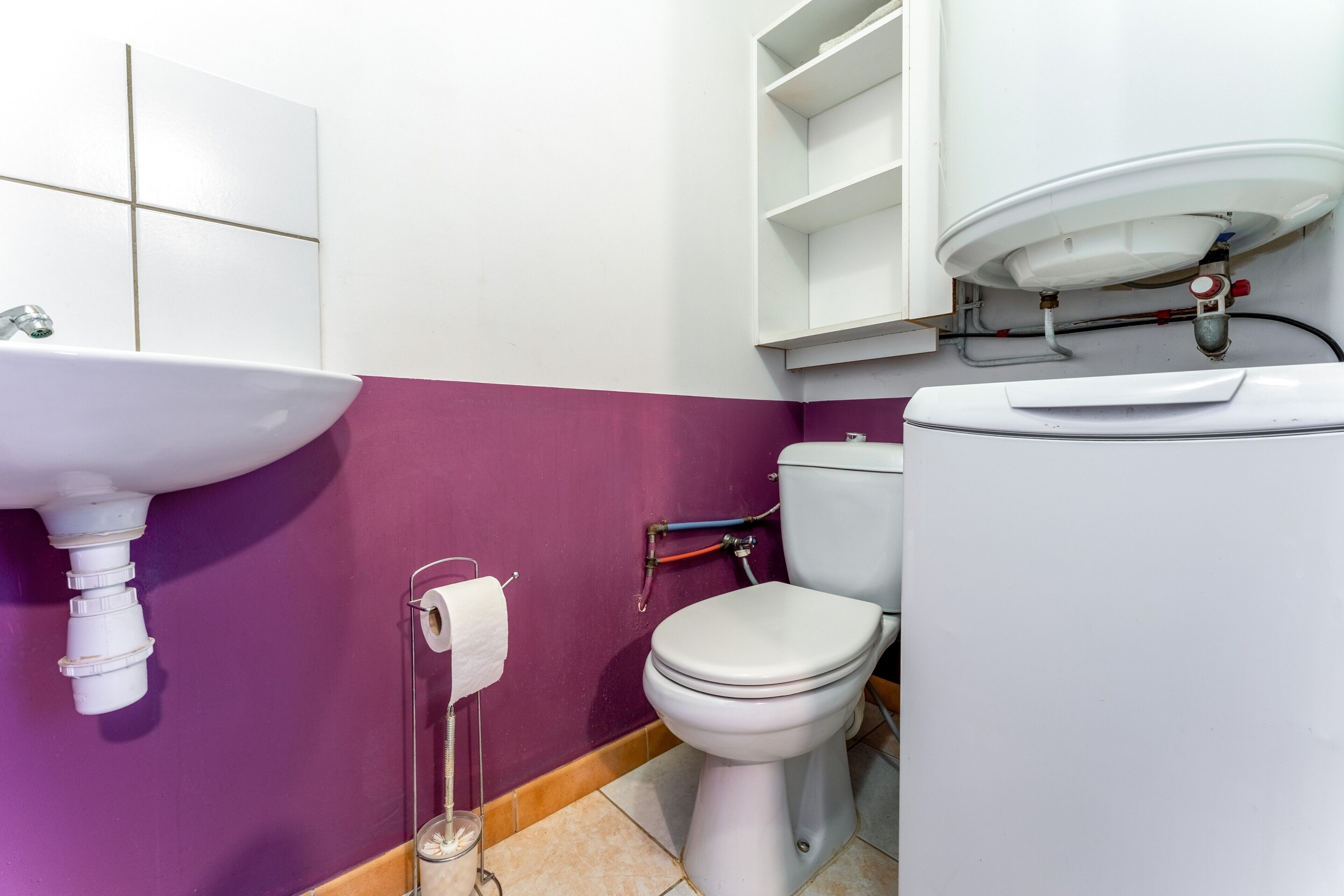 Un baño con lavamanos, inodoro y pared morada.
