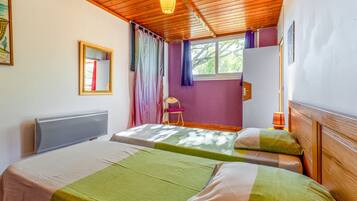 Una habitación con dos camas, una ventana con cortinas, un radiador y una silla.