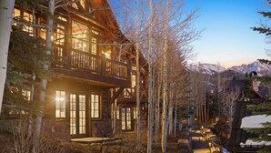 A log cabin with a balcony, surrounded by trees and a mountain backdrop. - See Forever Luxury Cabin - Walk to Gondola + Views (Mountain Village)