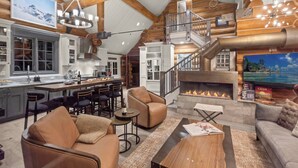 Un vaste espace de vie doté d’une cheminée, une cuisine avec un bar et un escalier menant à un niveau supérieur.