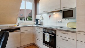 Een moderne keuken met een vaatwasser, oven, magnetron en een raam dat voor natuurlijk licht zorgt.