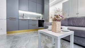 Una cocina moderna con armarios grises, una encimera blanca y un florero con flores sobre una mesa.