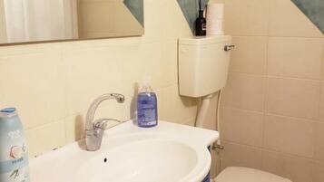 Een douche, handdoeken, zeep, toiletpapier