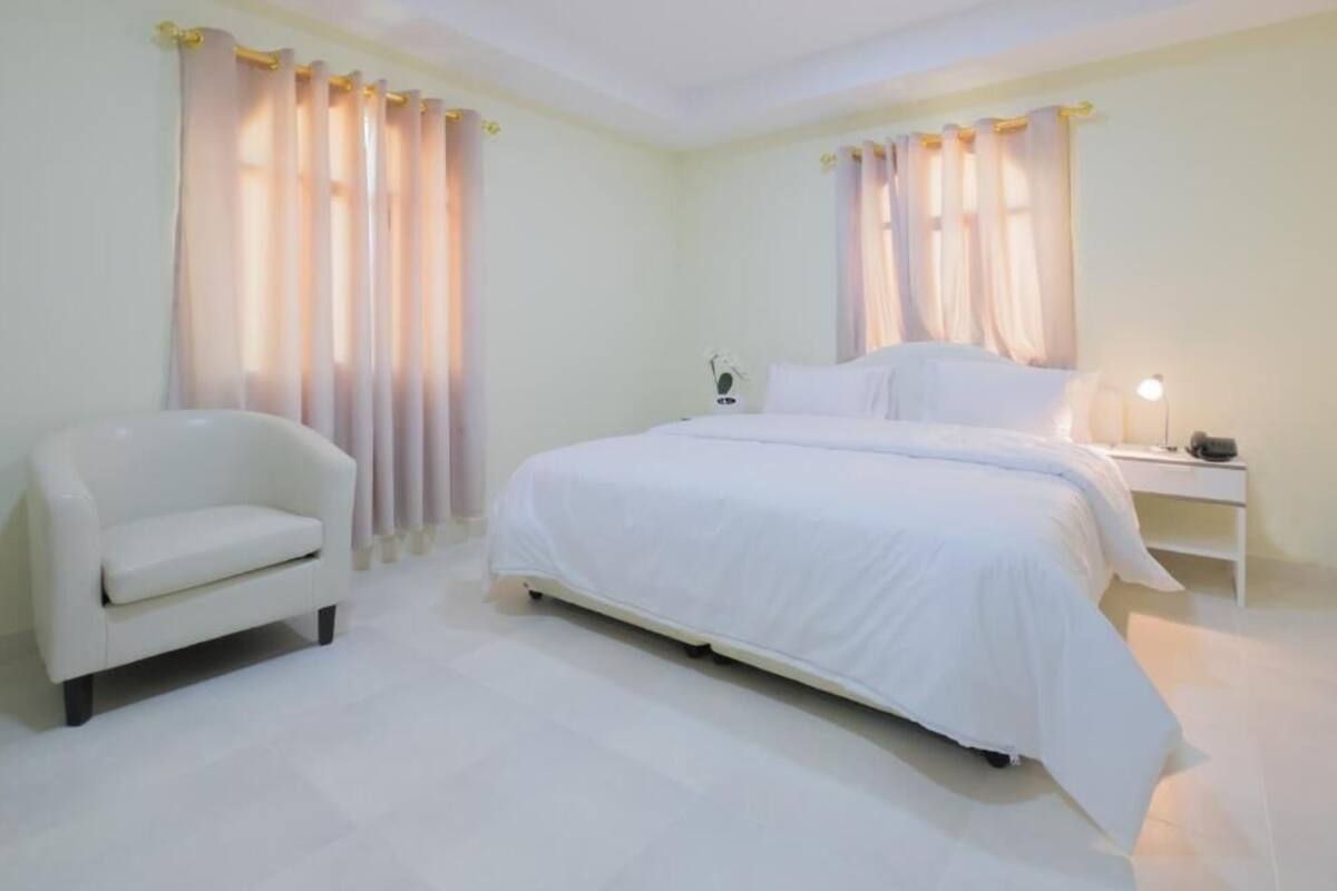 A bedroom with a bed, a bedside table, a lamp, and a chair.