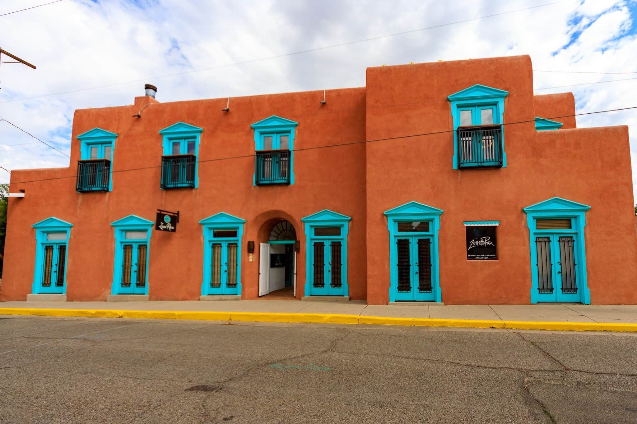 A building with a flat facade, multiple windows with blue trim, and a yellow curb.
