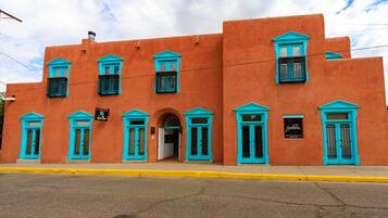 A building with a flat facade, multiple windows with blue trim, and a yellow curb.