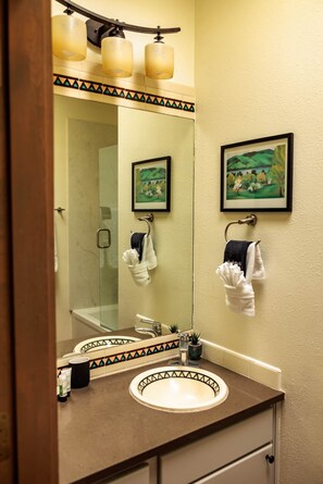 Une salle de bain avec un grand miroir, un lavabo et deux serviettes suspendues à des crochets.