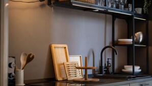 A kitchen with a modern design, featuring a black countertop, wooden utensils, a cutting board, and a sink. - Maison Amelie – Design Apartment | Milano Centrale (Milan)