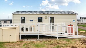 Une maison mobile de plain-pied, dotée d’un petit porche et d’une rampe menant à l’entrée.