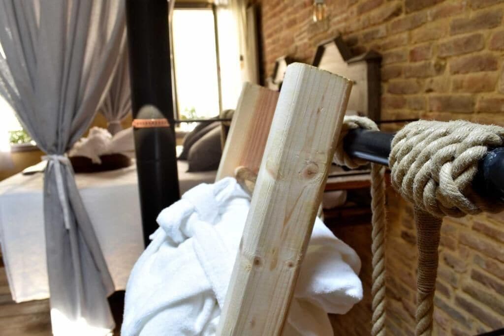 A wooden beam with a rope tied around it, a white towel, and a brick wall in the background.
