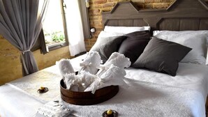 A neatly made bed with white linens, a wooden headboard, and a decorative white arrangement on the bed.