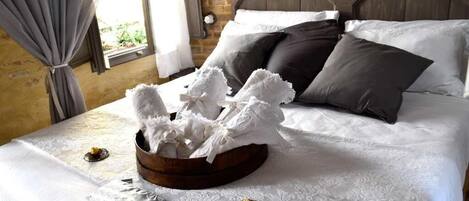A neatly made bed with white linens, a wooden headboard, and a decorative white arrangement on the bed.