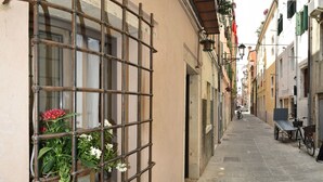 A narrow cobblestone street with buildings on either side, a metal gate, and a bicycle parked on the right.