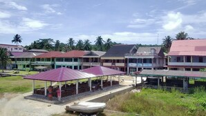 A row of buildings with a covered outdoor seating area and a small boat in the foreground.