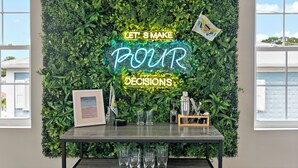 A room with a green wall, a neon sign, a framed picture, and a bar area with glasses and bottles. - Queen's Promise - King Suite - AC - Walkable (Christiansted)