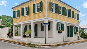 A two-story yellow building with green shutters, a covered porch, and a 'ONE WAY' sign. - Queen's Promise - King Suite - AC - Walkable (Christiansted)