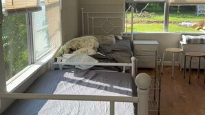 A bedroom with a bed, a desk, and a window.