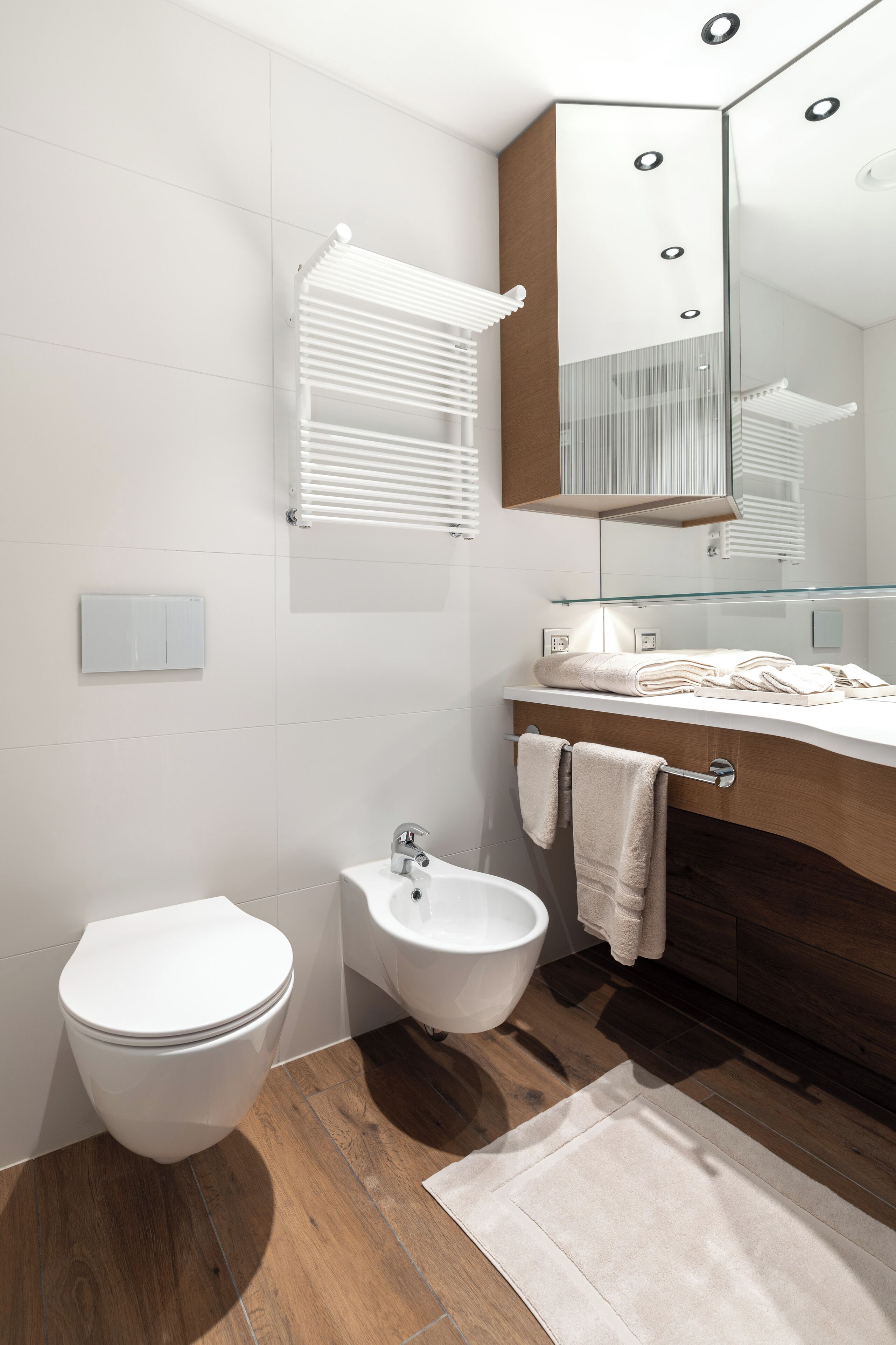 A modern bathroom with a toilet, bidet, and vanity with a mirror.