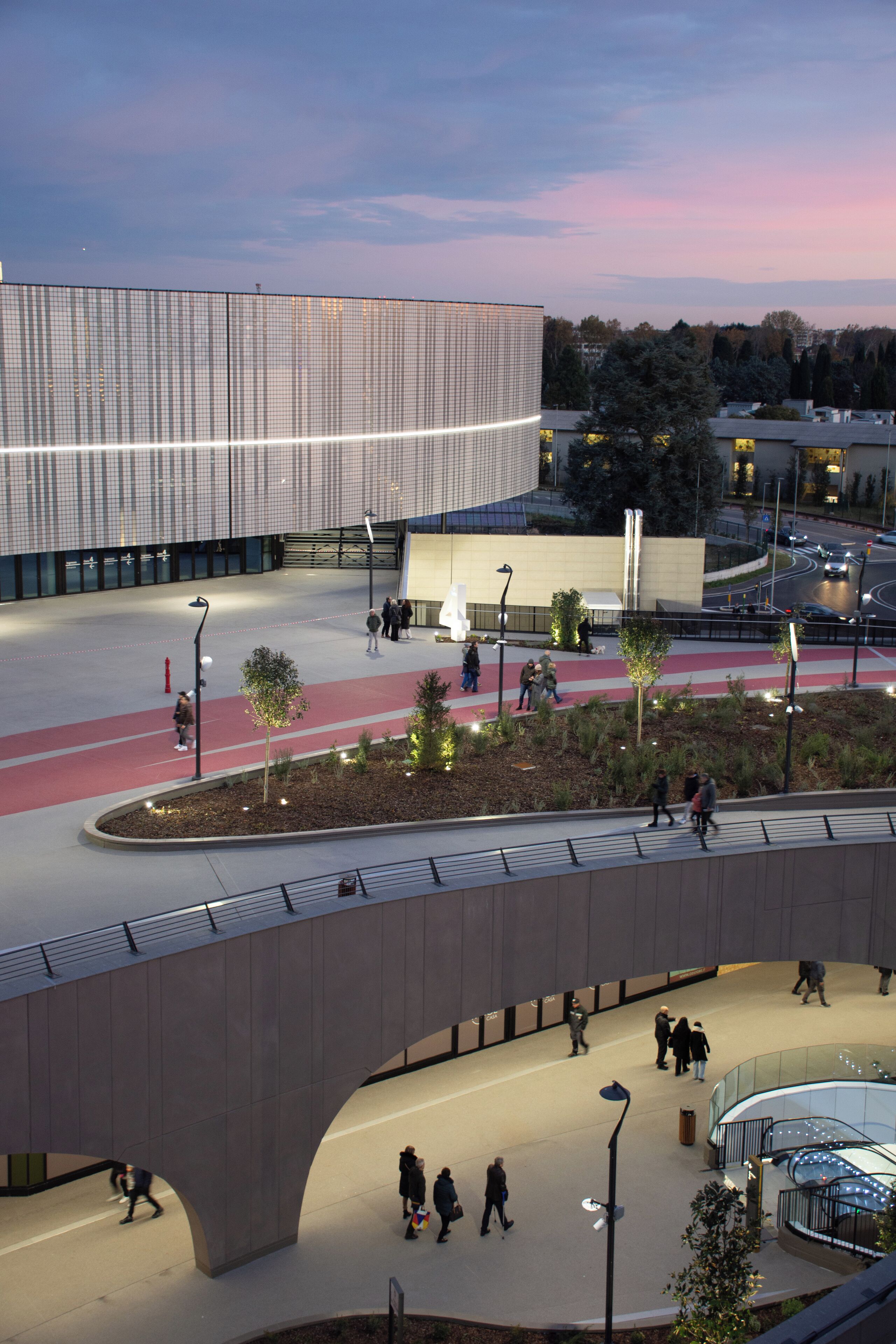 An urban plaza with a modern building, pedestrian paths, and a bridge.