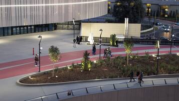 An urban plaza with a modern building, pedestrian paths, and a bridge.