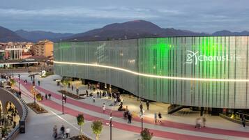 Een modern gebouw met een golvende glazen gevel en een groen LED-scherm.