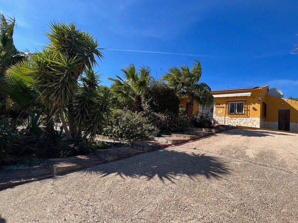 A residential property with a paved driveway, a stone pathway leading to the entrance, and a yellow house with a satellite dish. - Villa in Alcaucin - Sleeps 4 - Pool - Parking (Alcaucin)