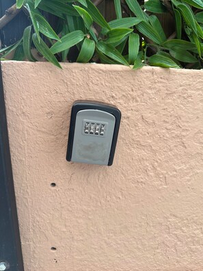 Ein Keypad an einer strukturierten Wand, umgeben von grünem Grünzeug.