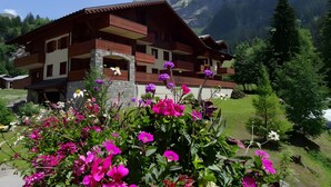 A multi-story building with balconies, surrounded by lush greenery and mountains in the background. - Les Préséloignés Apartment with Mountain View (Pralognan-la-Vanoise)