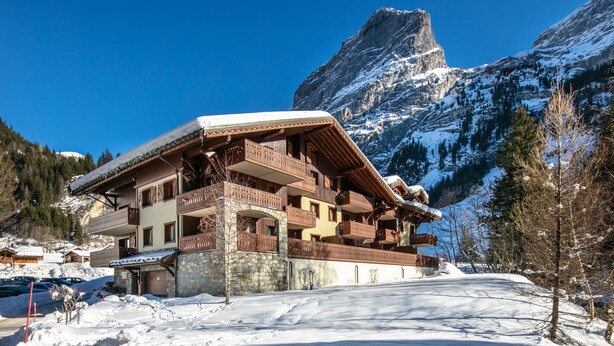 A multi-story chalet with balconies, a stone foundation, and a mountain backdrop. - Les Préséloignés Apartment with Mountain View (Pralognan-la-Vanoise)