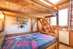 Une pièce en bois avec un lit superposé, une échelle, un radiateur et une fenêtre avec des rideaux.