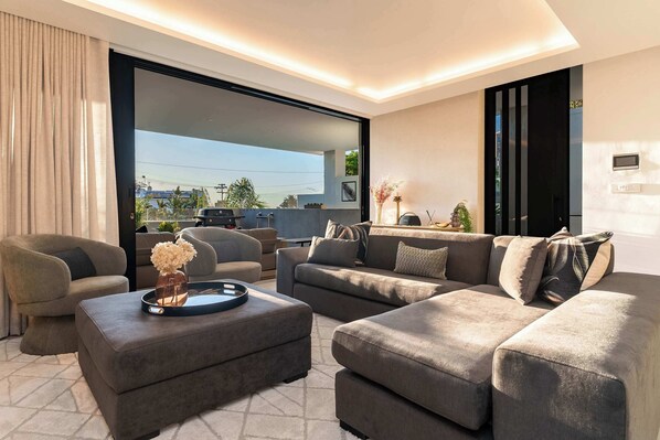 A modern living room with a sectional sofa, ottoman, and a large window.
