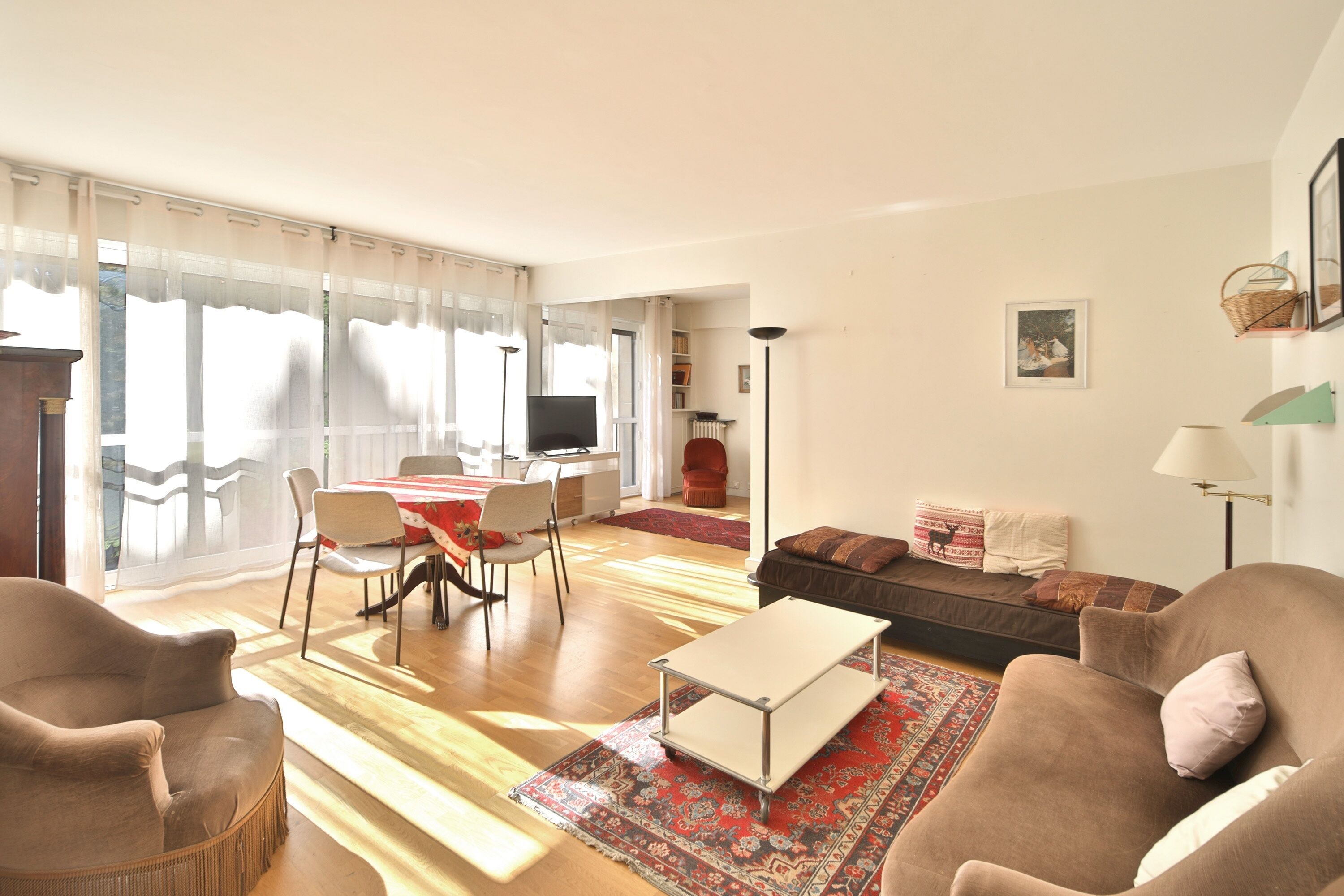 A living room with a sofa, chairs, a coffee table, and a dining area with a table and chairs.