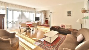 Ein Wohnzimmer mit einer Couch, Sesseln, einem Couchtisch und einem Essbereich mit Tisch und Stühlen.