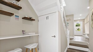 Un interior moderno con una escalera, paredes blancas y suelo de madera.