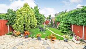 A garden patio with a stone floor, surrounded by a red fence, and various potted plants and garden statues. - Central Location, Sleeps 7, 4 Bedrooms, Parking for 4+ cars, easy walk to town (Stratford-upon-Avon)