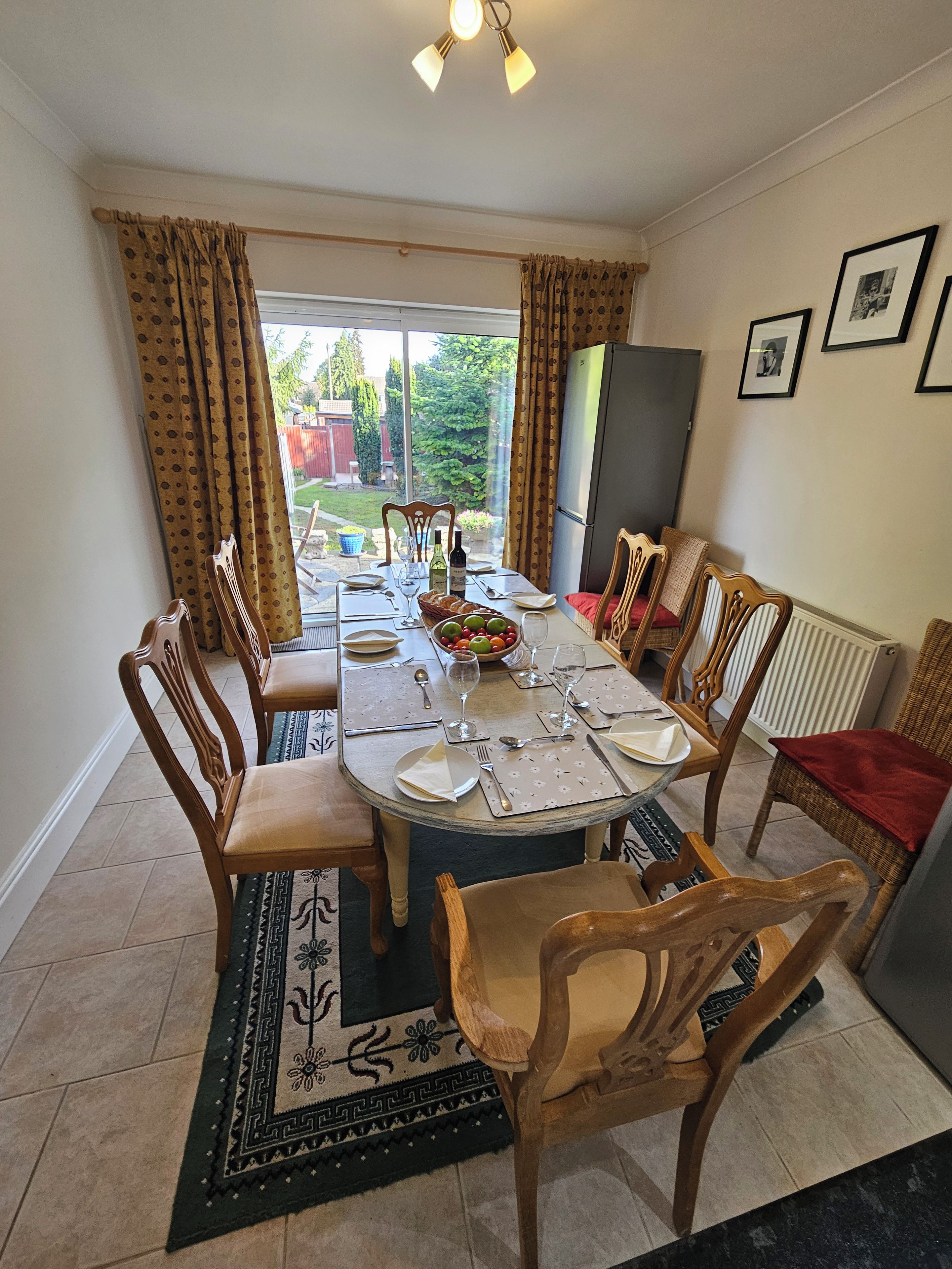 A dining room with a round table set for six, surrounded by wooden chairs.