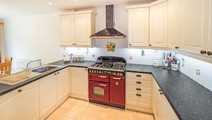 A kitchen with white cabinets, a red stove, and a black countertop. - Central Location, Sleeps 7, 4 Bedrooms, Parking for 4+ cars, easy walk to town (Stratford-upon-Avon)