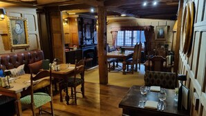 A traditional inn with wooden floors, leather seating, and a fireplace. Tables are set for dining with chairs and table settings. - Central Location, Sleeps 7, 4 Bedrooms, Parking for 4+ cars, easy walk to town (Stratford-upon-Avon)