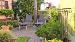A patio with two lounge chairs, a potted plant, and a small garden area. - Holiday Apartment Havelnixe with Private Terrace and Wi-Fi (Bahnitz)