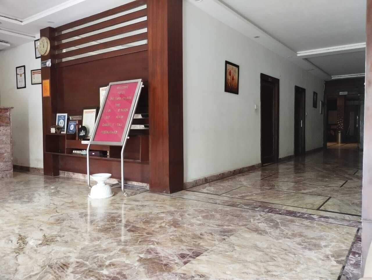 A lobby with a marble floor, a reception desk, and a signboard.