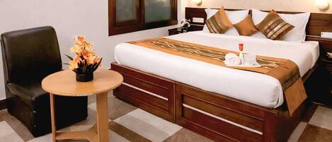 A hotel room with a bed, a chair, a small table, and a window.