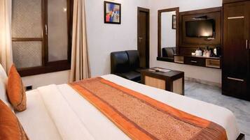 A hotel room with a bed, a desk, a television, and a ceiling fan.
