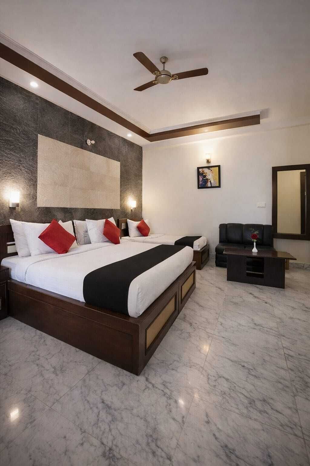 A hotel room with a large bed, a ceiling fan, a flat-screen TV, and a marble floor.