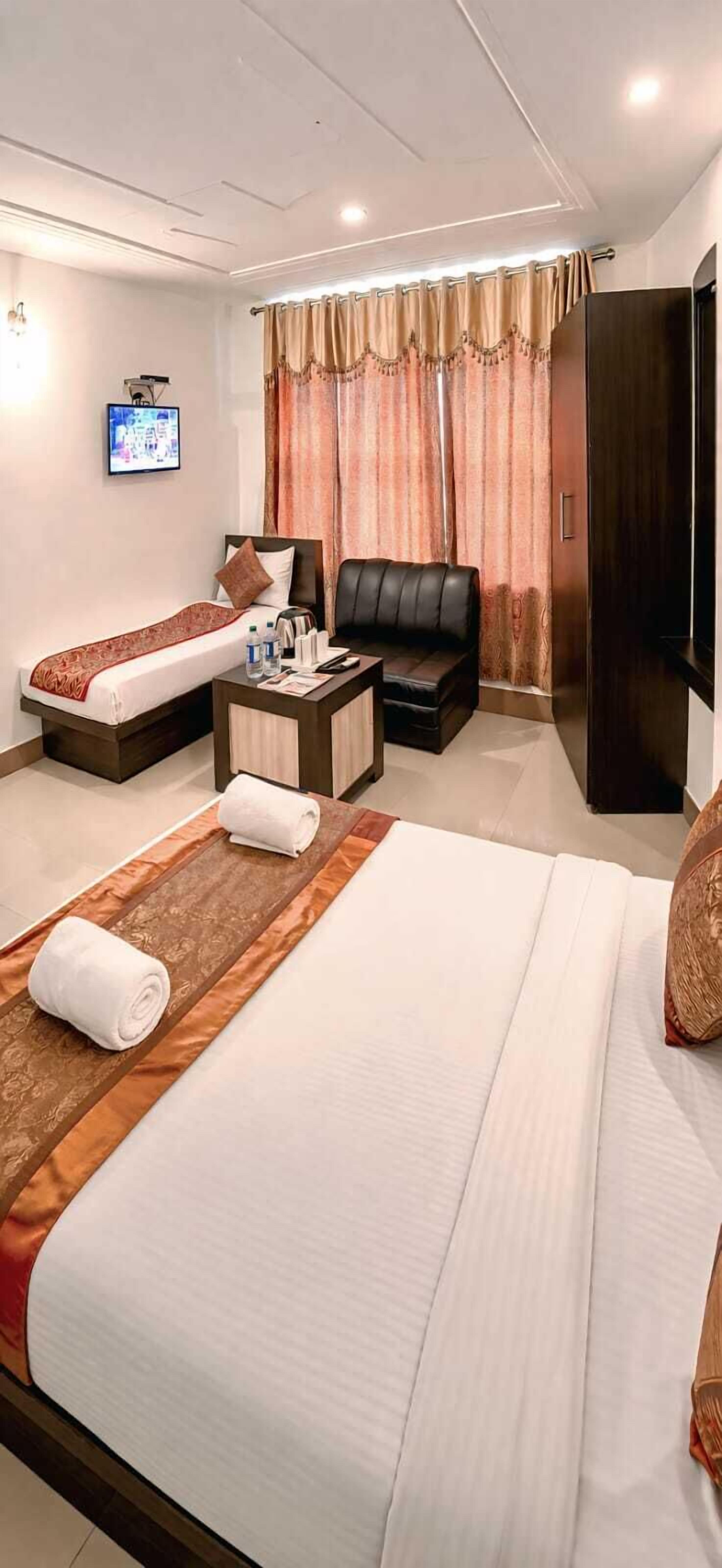 Une chambre d’hôtel comprenant un lit, un canapé, une table basse, une télévision et une armoire.