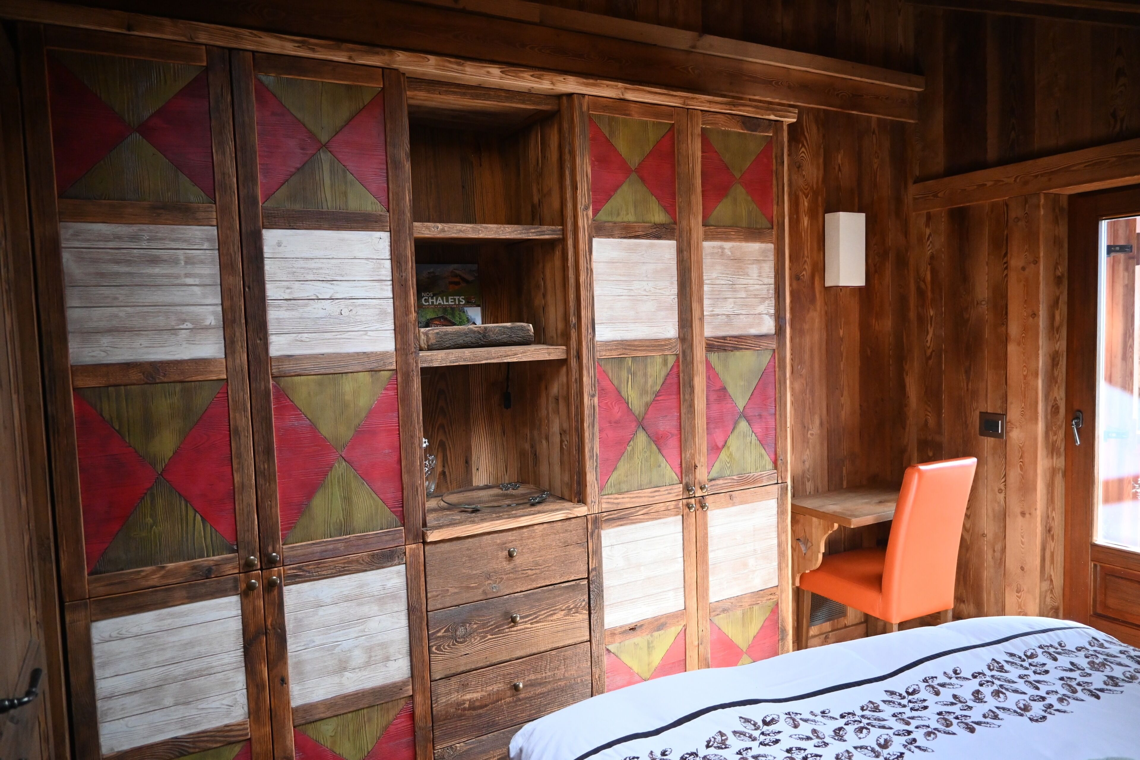 A wooden room with a bed, a desk, and a chair.