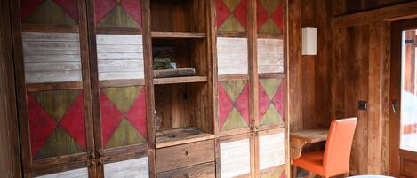 A wooden room with a bed, a desk, and a chair.