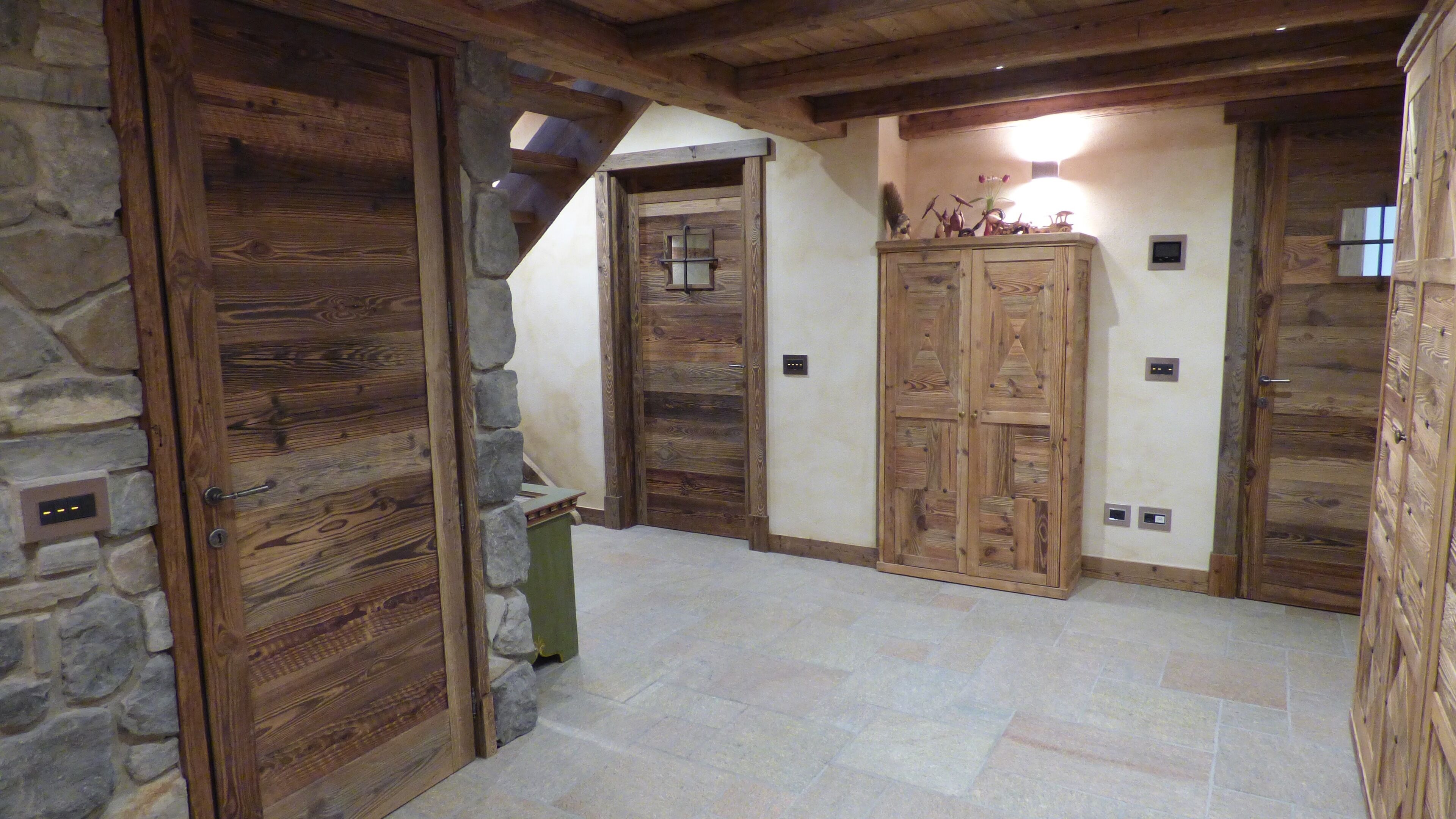 A rustic interior with wooden doors, stone walls, and a stone floor.