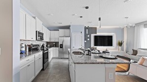 Una cucina moderna con mobili bianchi, elettrodomestici in acciaio inossidabile e un piano di lavoro in granito.