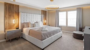 Camera da letto moderna con un letto grande, comodini, una scrivania e vista all'esterno tramite ampie finestre.